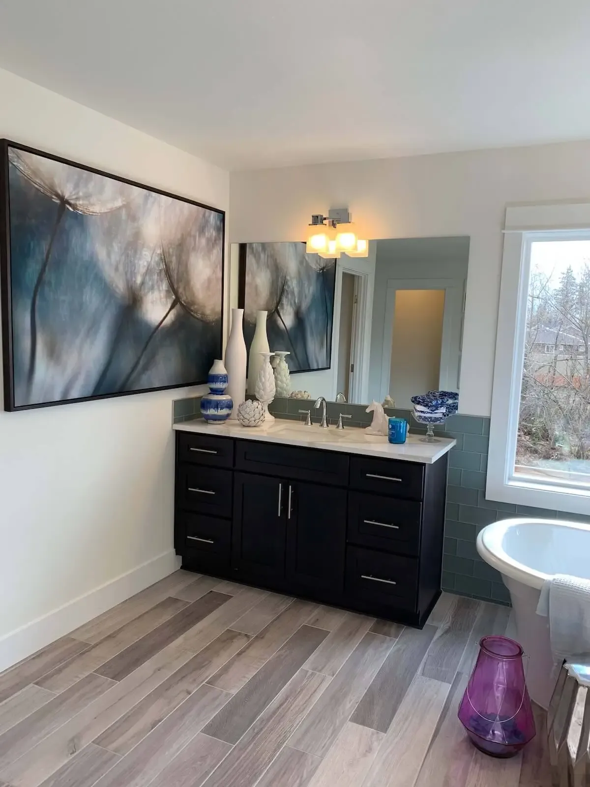 elegantly decorated bathroom with abstract painting on the wall, decorative cases, and wonderful light over a hardwood floor