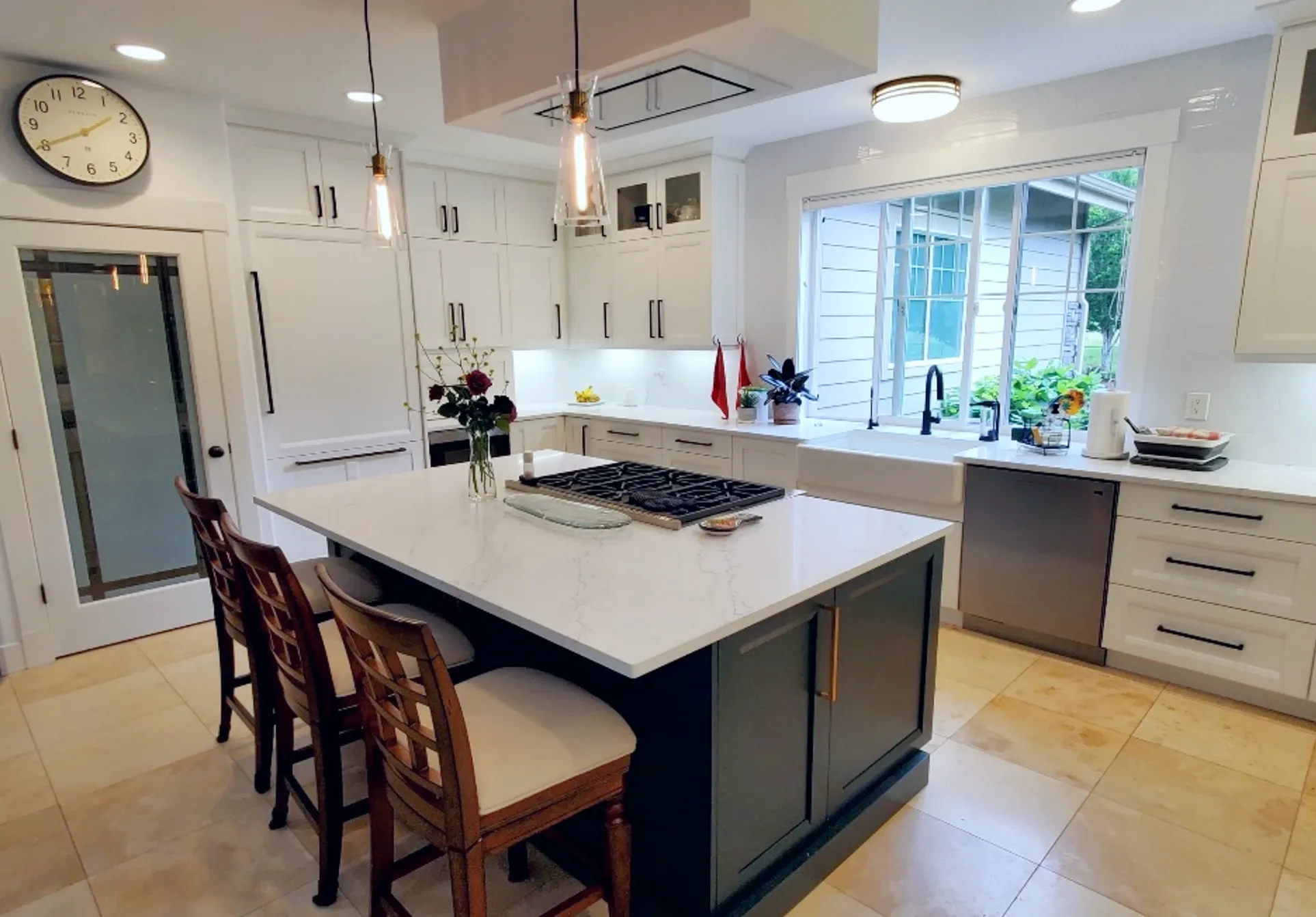 a sleek, modern kitchen with white cabinetry and a fridge that merges seemlessly into the surrounding cabinets. Modern chairs sit at the cabinet.