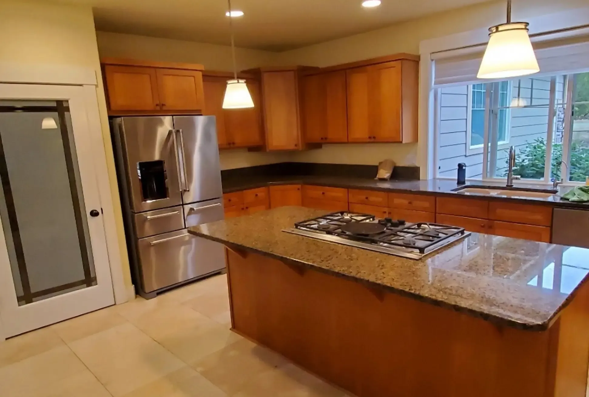 a dated-looking kitchen with stained wooden cabinets and a fridge that protrudes into the room